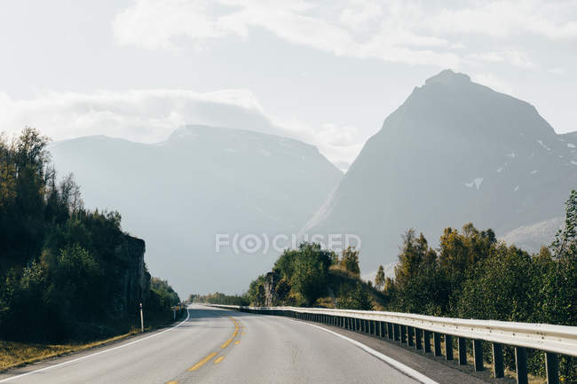 Malerischer Blick auf die leere Straße über neblige Berge im Hintergrund — Stockfoto