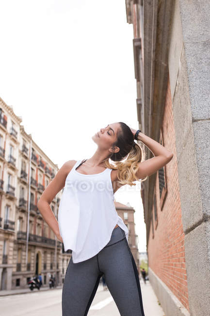 Mujer deportiva posando con los ojos cerrados en la escena de la calle - foto de stock