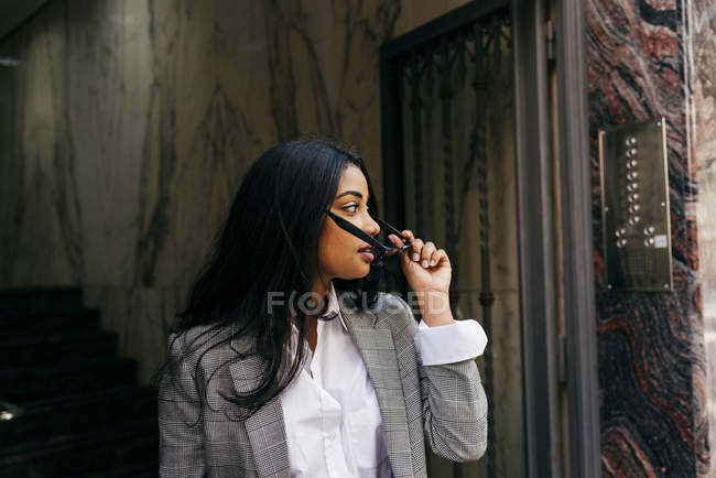 Portrait of stylish businesswoman putting on sunglasses — Stock Photo