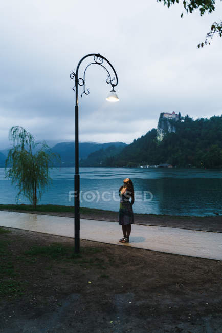 Брюнетка жінка, стоячи на алеї та переглядають ліхтарний стовп — стокове фото