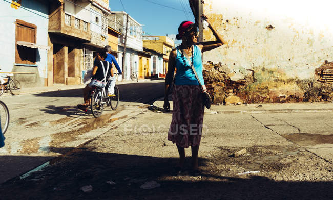 Cuba - 27. august 2016: frau steht am straßenszenario und blickt weg auf hintergrund eines armen viertels. — Stockfoto