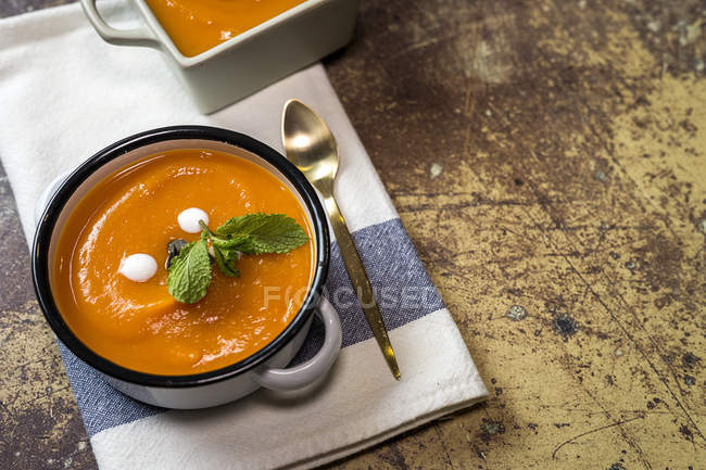 Close up view of cream of pumpkin with mint leaves in sauce pot — Stock Photo