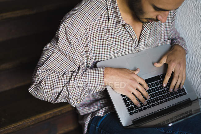 Crop man with laptop sitting on staircase — Stock Photo