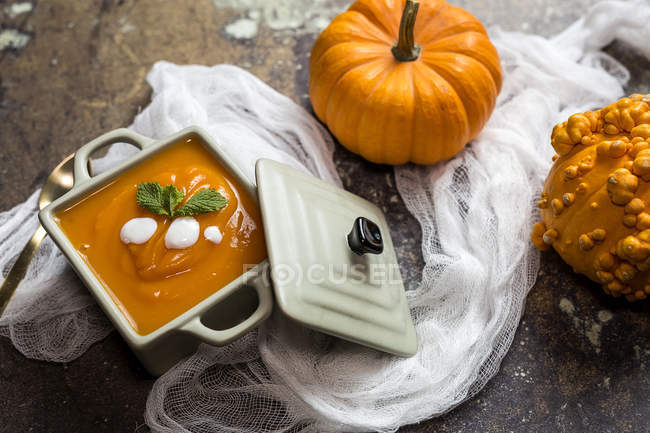 Close up view of pumpkin creme soup in ceramic bowl on towel — Stock Photo
