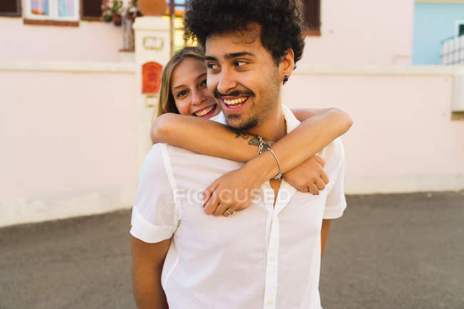 Усміхнений чоловік носить молоду дівчину на спині — стокове фото