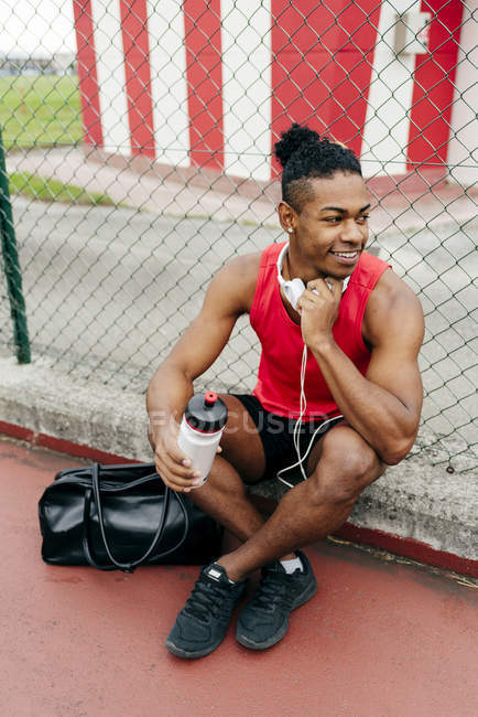 Deportista sonriente descansando después del entrenamiento y mirando hacia otro lado - foto de stock