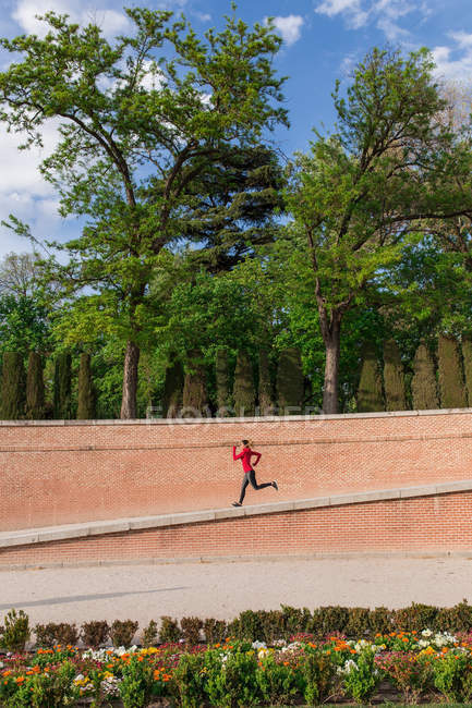 Vista lateral de la chica corriendo en el parque de la ciudad - foto de stock