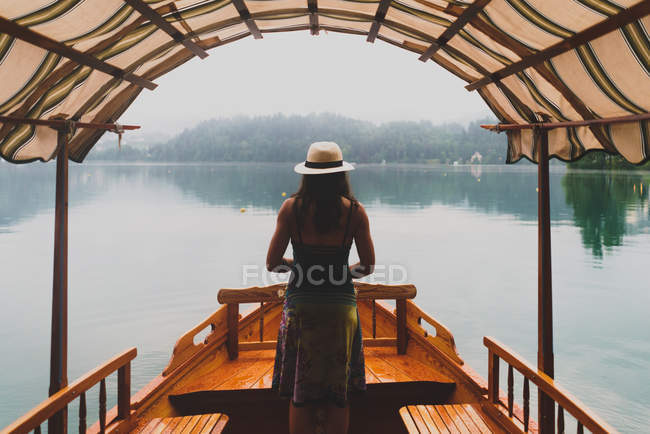 Vue arrière de la femme brune posant sur le bateau sur le lac — Photo de stock