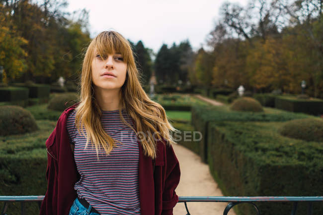 Chica morena romántica posando en parque verde y mirando a un lado - foto de stock