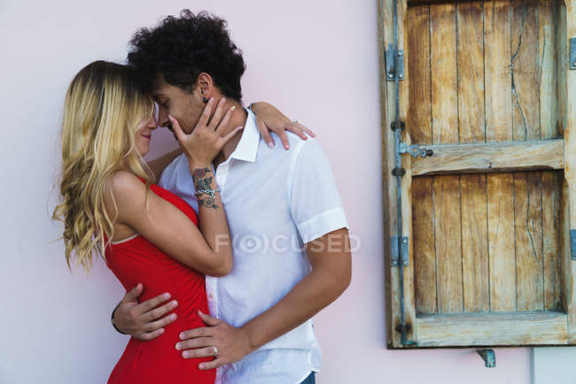 Side view of young elegant couple embracing in passion on background of street wall. — Stock Photo