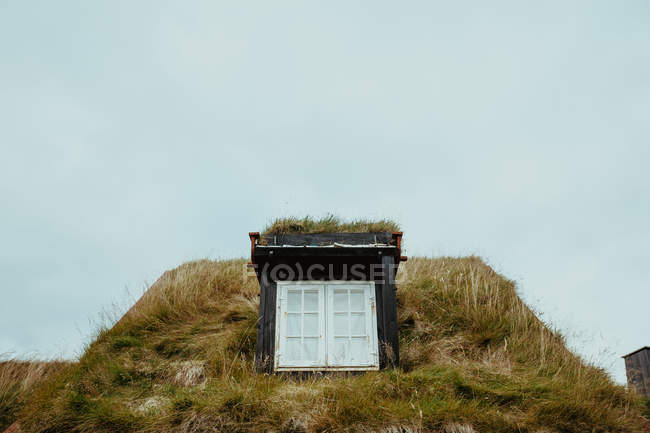 Window in house roof covered with grass over misty sky — Stock Photo