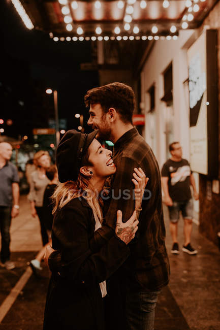 Веселая пара обнимается на вечерней улице — стоковое фото