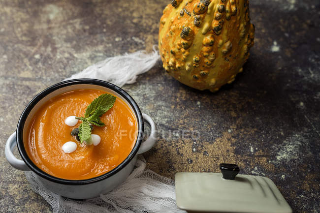 Still life with cream of pumpkin in sauce pot on stone surface — Stock Photo