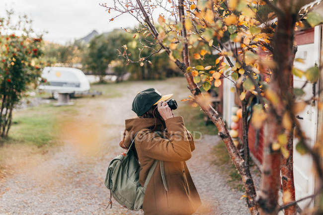 Seitenansicht einer Person beim Fotografieren von Haus mit Kamera. — Stockfoto