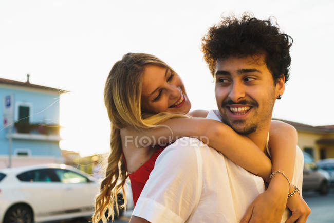 Man carrying young girl on back and looking over shoulder at street scene — Stock Photo