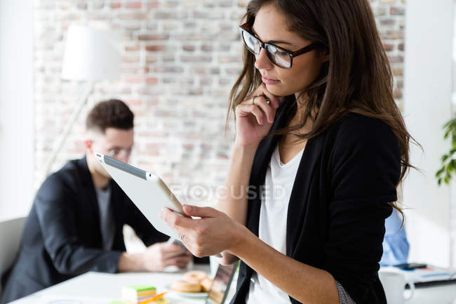 Ritratto di giovane imprenditrice in cerca di tablet digitale in un ufficio moderno — Foto stock