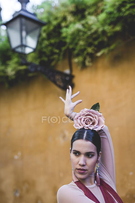 Flamenco dancer with flower decoration on head posing over street wall with lantern — Stock Photo