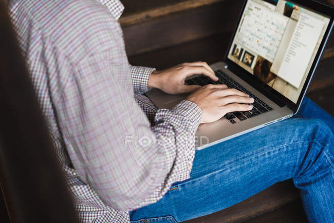 Crop macho sentado na escada com laptop — Fotografia de Stock