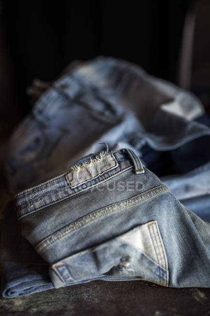 Nahaufnahme einer blauen Jeanshose auf einem dunklen Tisch. — Stockfoto