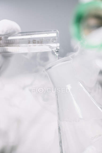 Científico de cultivos añadiendo líquido en el frasco - foto de stock