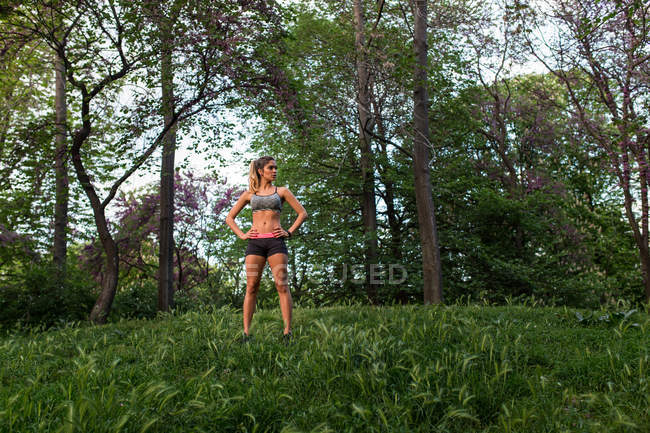 Ajuste deportista posando en el césped en el parque de la ciudad - foto de stock