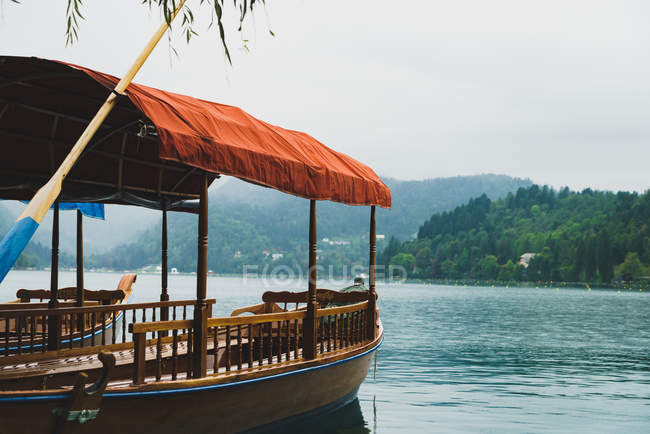 Пустая пришвартованная лодка с навесом ткани на озере над горным ландшафтом — стоковое фото