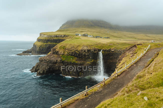 Panoramic view of coastline with waterfall falling into ocean — Stock Photo