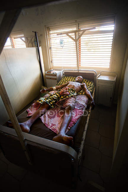 Benin, afrika - 31. august 2017: mann liegt auf bett in afrikanischem krankenhaus — Stockfoto