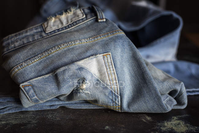 Nahaufnahme einer blauen Jeanshose auf einem dunklen Tisch. — Stockfoto