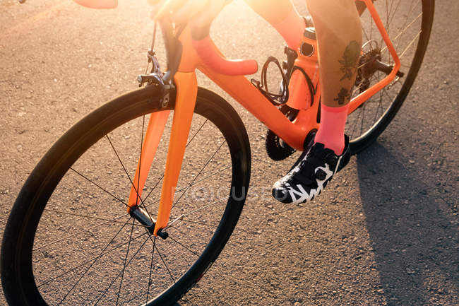 Low section of male cyclist riding bicycle on road — Stock Photo