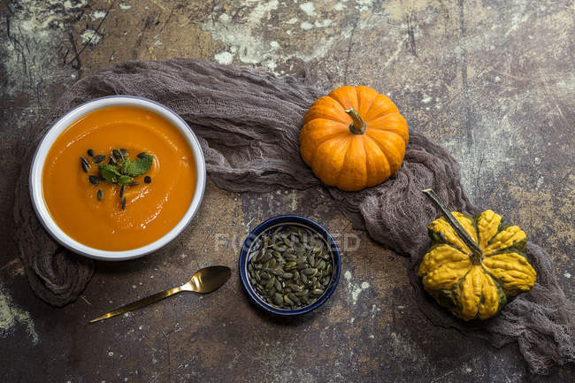 Still life with cream of pumpkin in bowl pumpkins on stone surface — Stock Photo