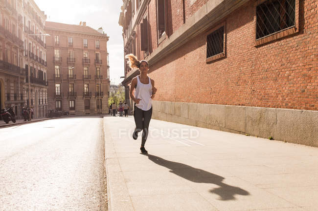 Menina loira em sportswear jogging na calçada — Fotografia de Stock