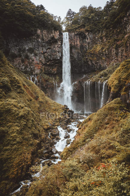 Cascada que fluye desde el acantilado rocoso verde - foto de stock