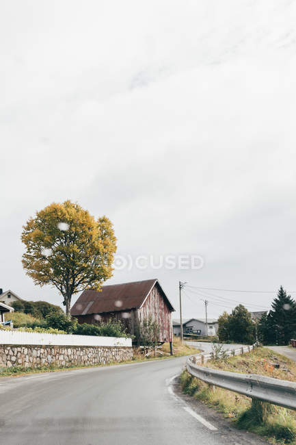 Asphalt road going along small village houses on gray day. — Stock Photo