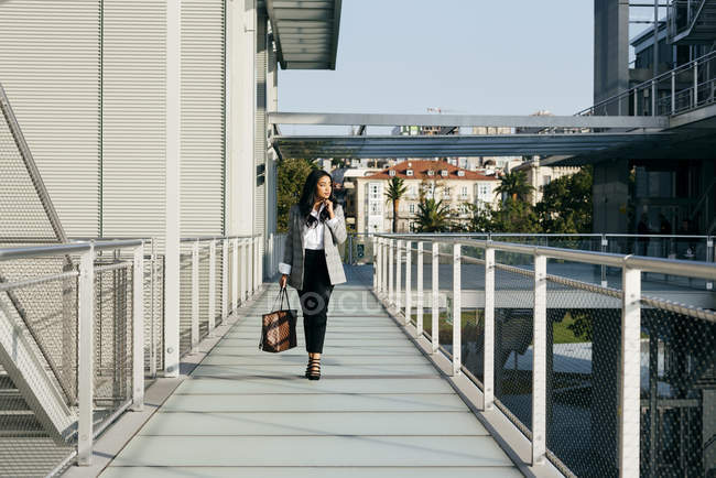 Portrait de femme élégante en vêtements élégants marchant sur le passage du balcon et regardant de côté — Photo de stock