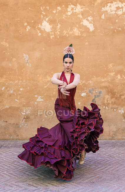 Вид спереди на танцовщицу фламенко, позирующую в типичном костюме над уличной стеной — стоковое фото
