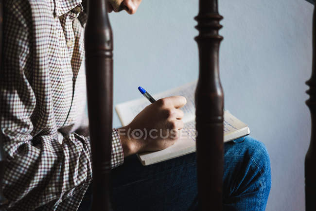 Мужчина сидит на лестнице и пишет в блокноте — стоковое фото