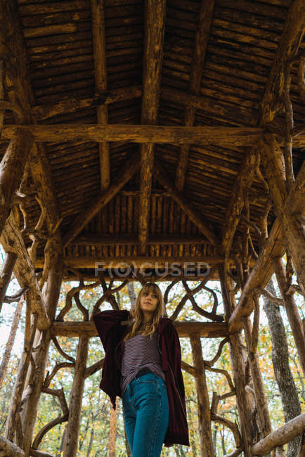 Низький кут зору брюнетка дівчина позує в дерев'яному проході — стокове фото
