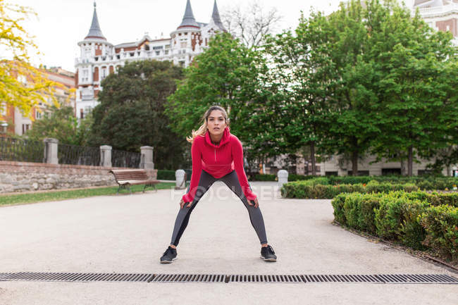 Portrait of girl in sportswear stretching at city park — Stock Photo