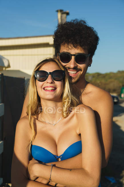 Ritratto di coppia che abbraccia guardando la macchina fotografica in spiaggia — Foto stock