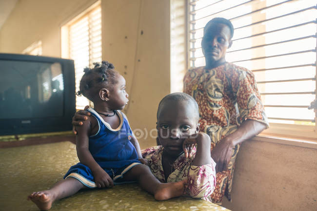 BENIN, AFRIQUE - 31 AOÛT 2017 : Homme avec des enfants en vêtements ethniques posant près de la table à la maison . — Photo de stock