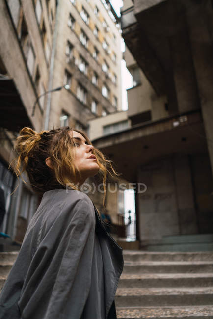 Trendy girl walking on stairs and looking at buildings — Stock Photo