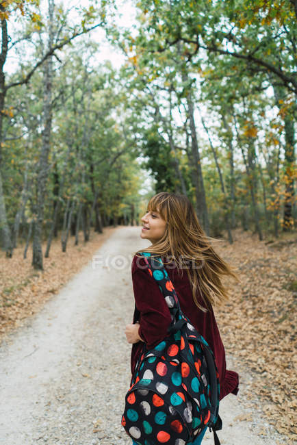 Btunette fille avec sac à dos marchant dans les bois — Photo de stock
