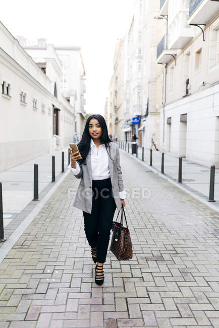 Elegant busineswoman walking with phone on street — Stock Photo