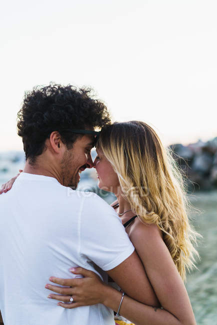 Задній вид на щасливу пару обіймаються на пляжі — стокове фото