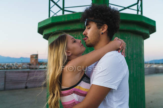 Side view of embracing couple having fun at dock — Stock Photo