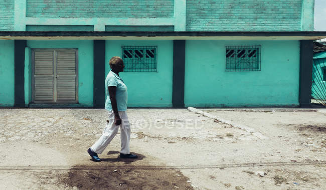 CUBA - 27 AGOSTO 2016: Vista laterale della donna che cammina lungo l'edificio blu — Foto stock
