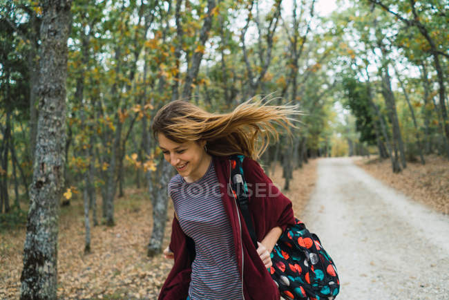 Menina alegre com mochila andando na floresta — Fotografia de Stock