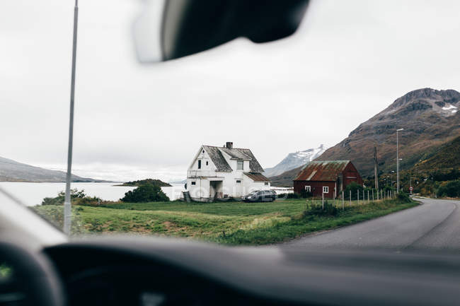 View of small house at mountains lake shore from car. — Stock Photo