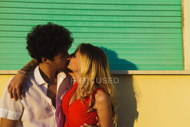 Любящая обнимающая пара целуется над уличным фасадом — стоковое фото